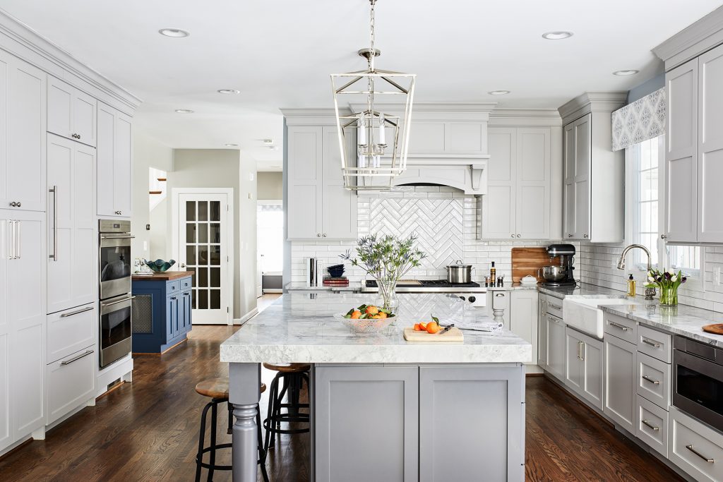 Large kitchen with lots of white cabinets lots of counter space and 4 light lantern pendant lamp above kitchen island with 2 stools