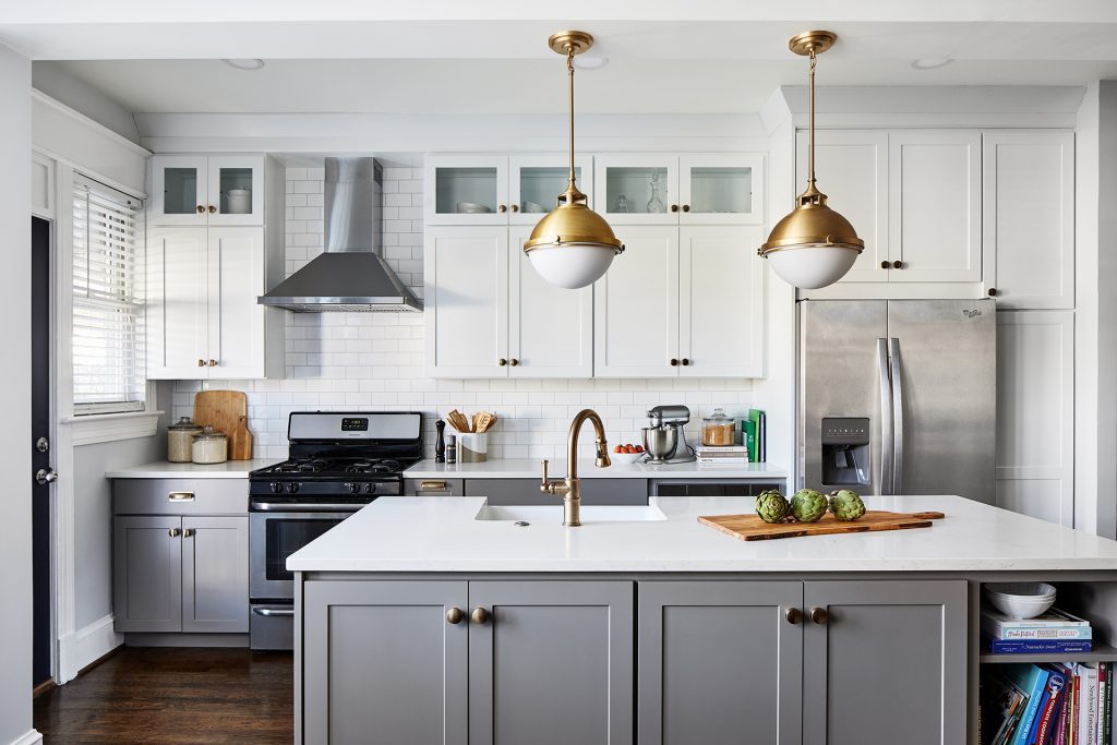 white subway tile featuring light grey wall cabinets with a classic farmhouse sink, white walls and light wood tones balanced and complemented by the hanging pendant lights